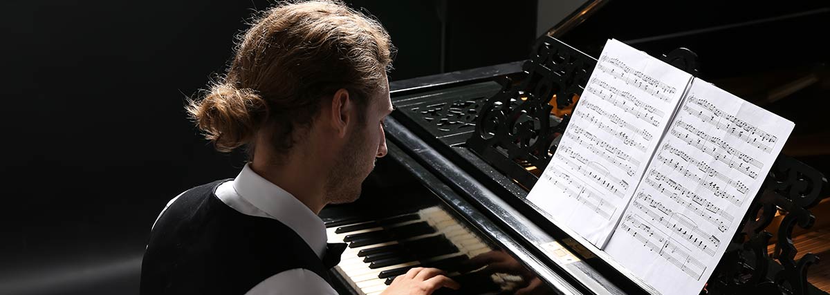 A man playing the piano whilst reading notes