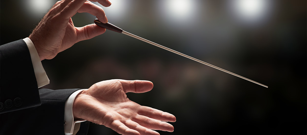 Conductor conducting an orchestra with audience in blurred background