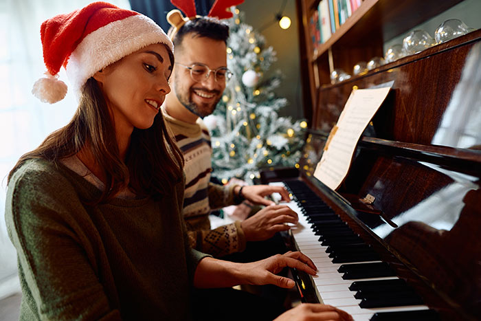 Couple wearing Christmas hat playing piano