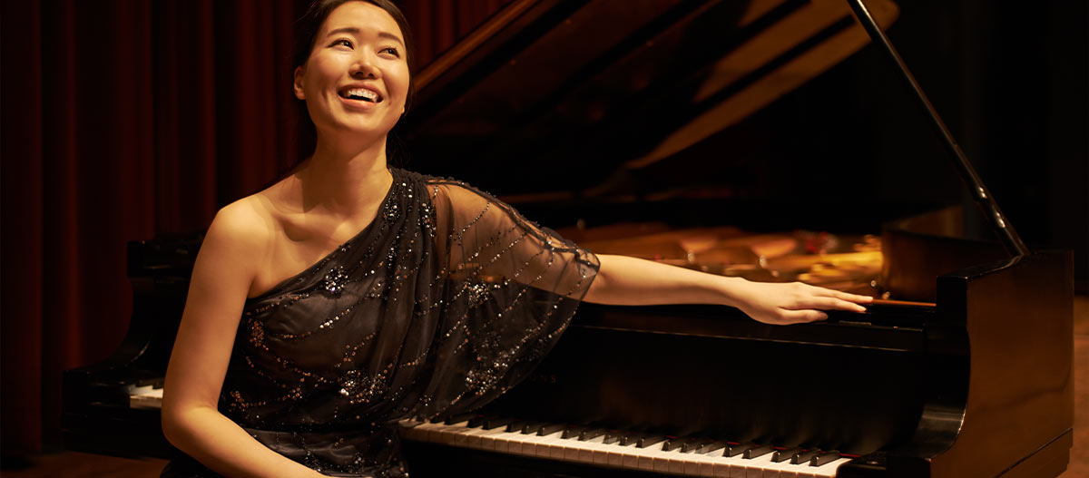 Elegant happy woman sitting with her hand on the piano