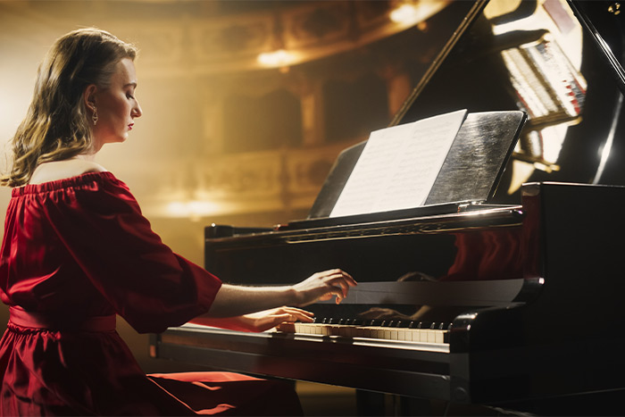 Elegant lady in red dress playing the grand piano on stage