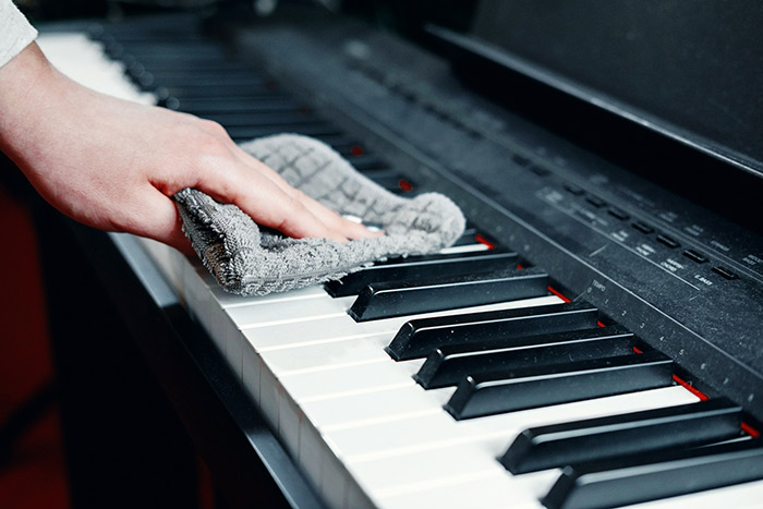 Hand wiping piano keyboard with towel