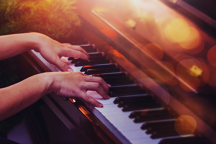 Hands playing piano in warm lighting