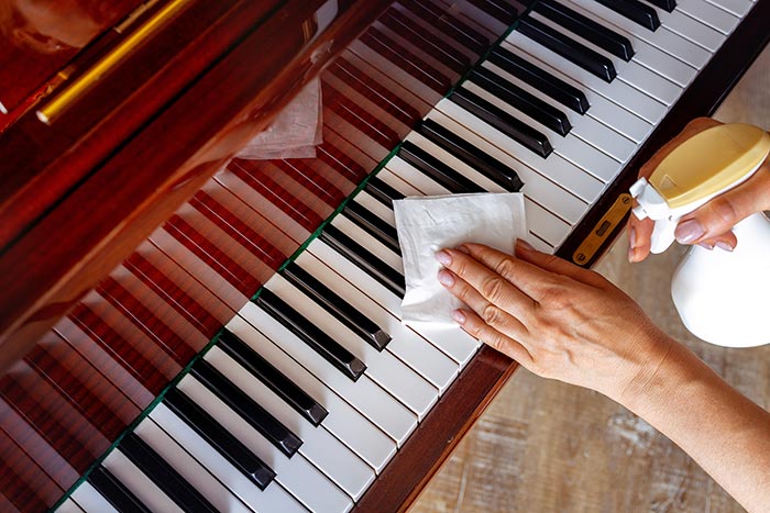 Hands wipes the piano with a wipes-and holding a spray bottles feat