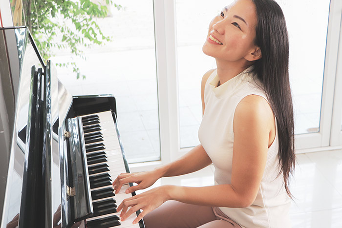 Happy woman playing piano at home