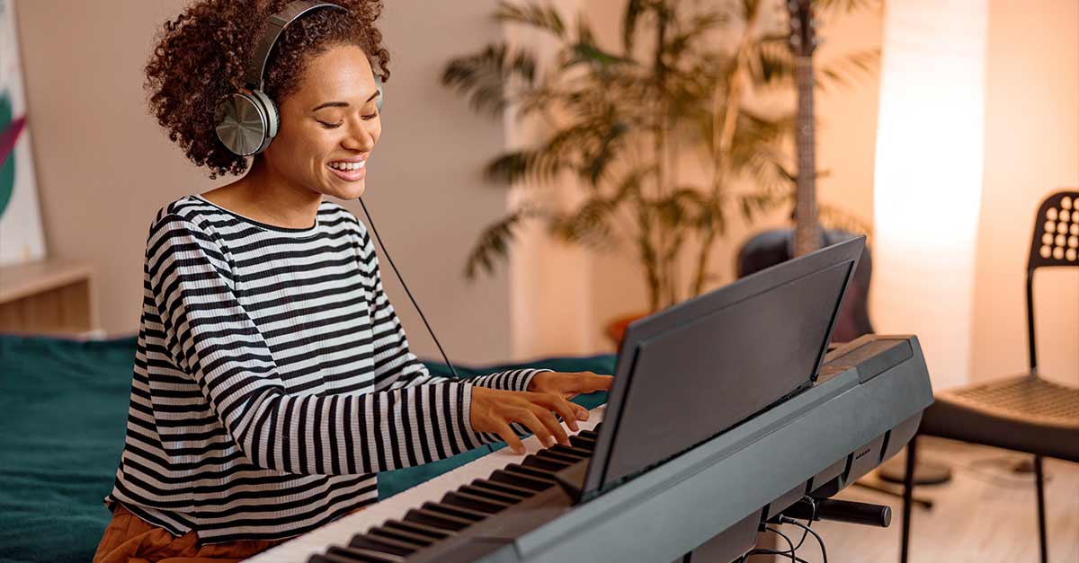 Happy woman playing piano with headphones on
