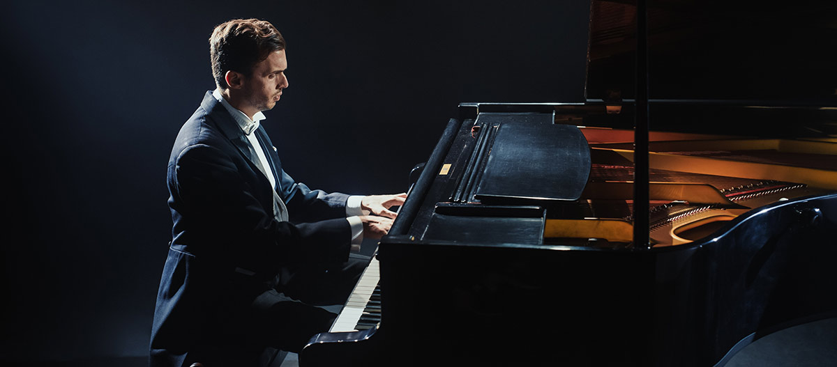 Man in suit playing the grand piano
