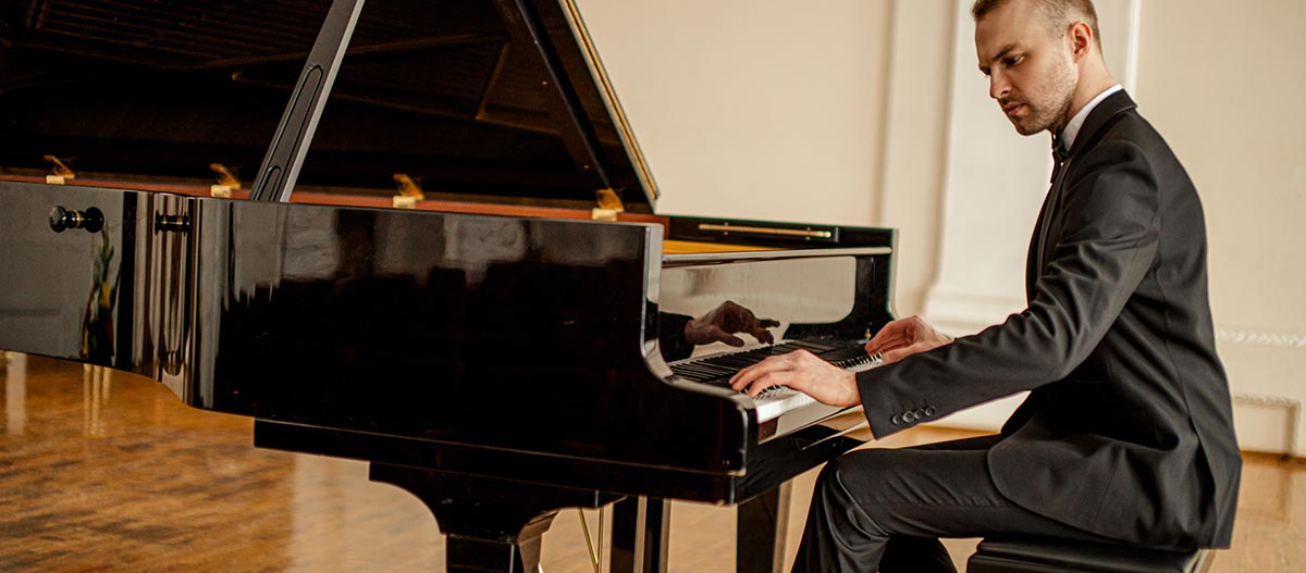 Man in suit seriously playing piano