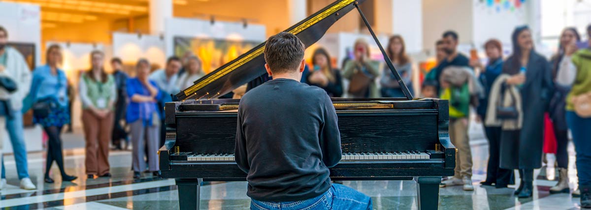 Man playing grand piano while people are watching