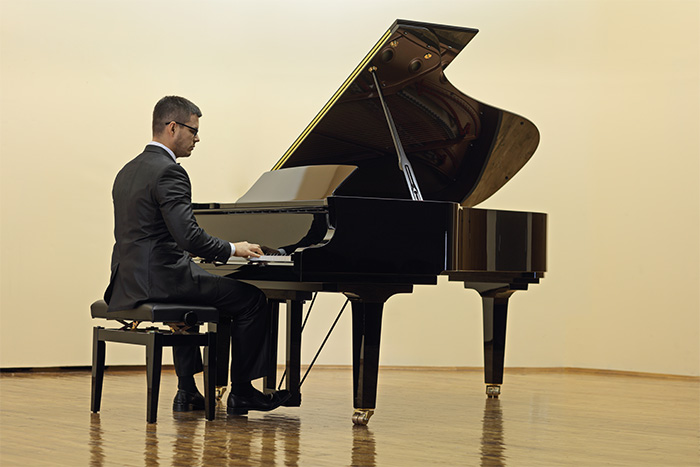 Man playing grand piano feat