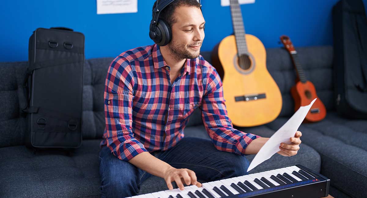 Man playing piano holding a music sheet