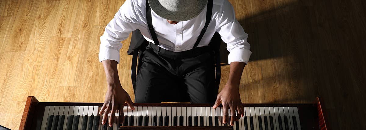 Man wearing a hat playing piano