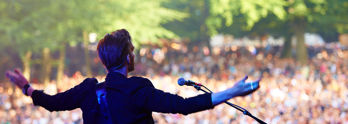 Musician performing on stage with crowd watching
