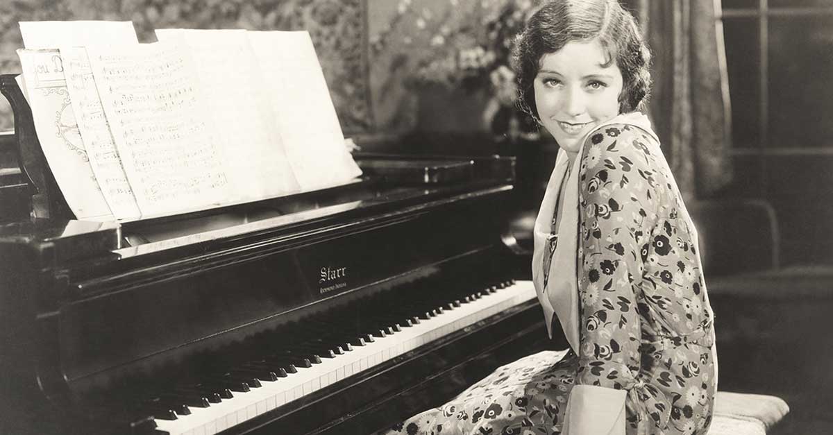 Old photo of a woman smiling sitting by the piano