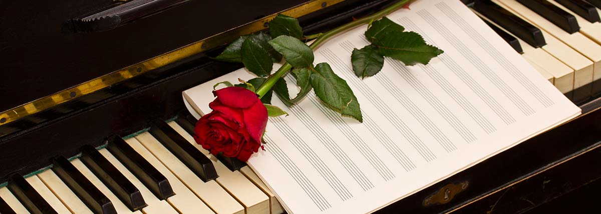 Red rose and music sheet on piano