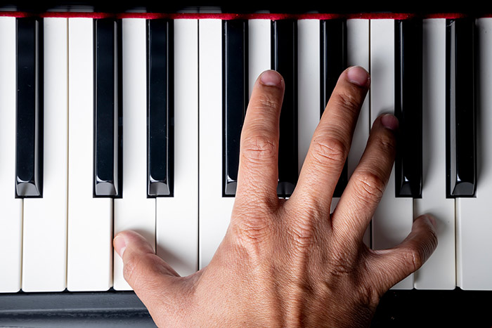 Right hand playing a D octave chord on the piano