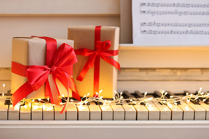 Two gift boxes and fairy lights on piano keys feat