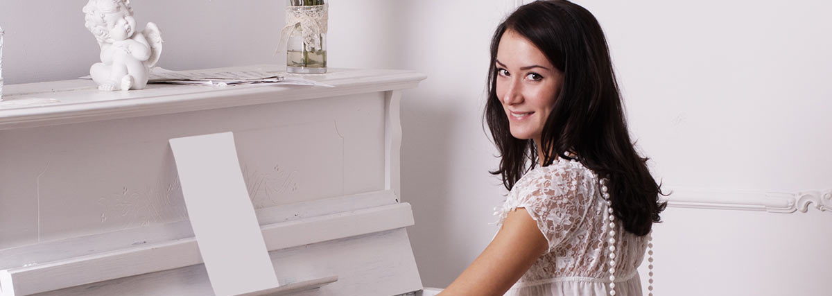 woman in white playing on white piano