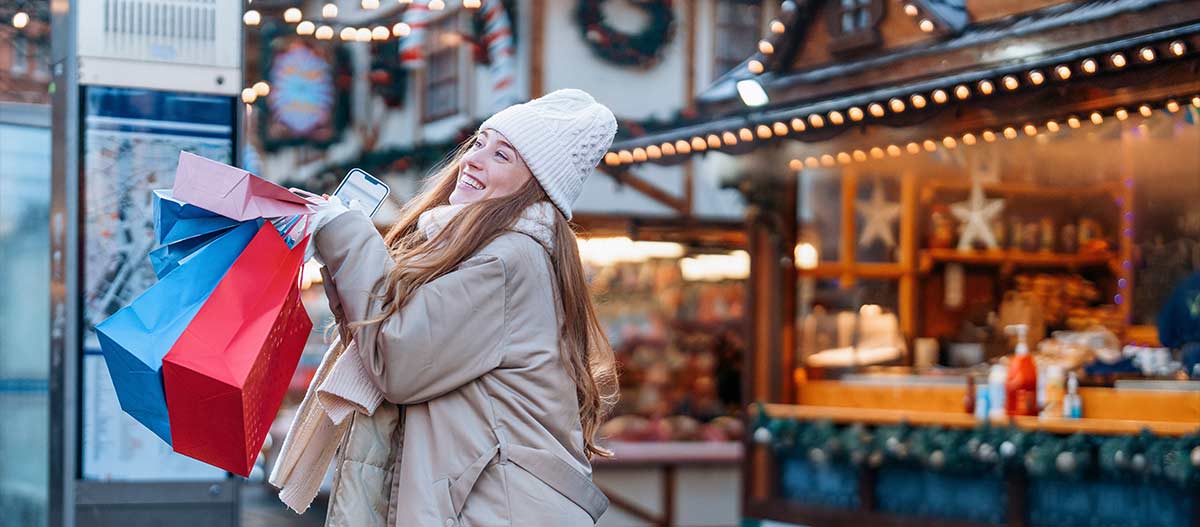 Woman in winter clothes holding Christmas gifts