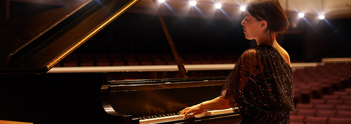 Woman playing grand piano emotionally on stage