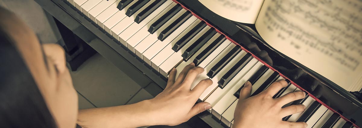 Woman playing piano looking at music sheet
