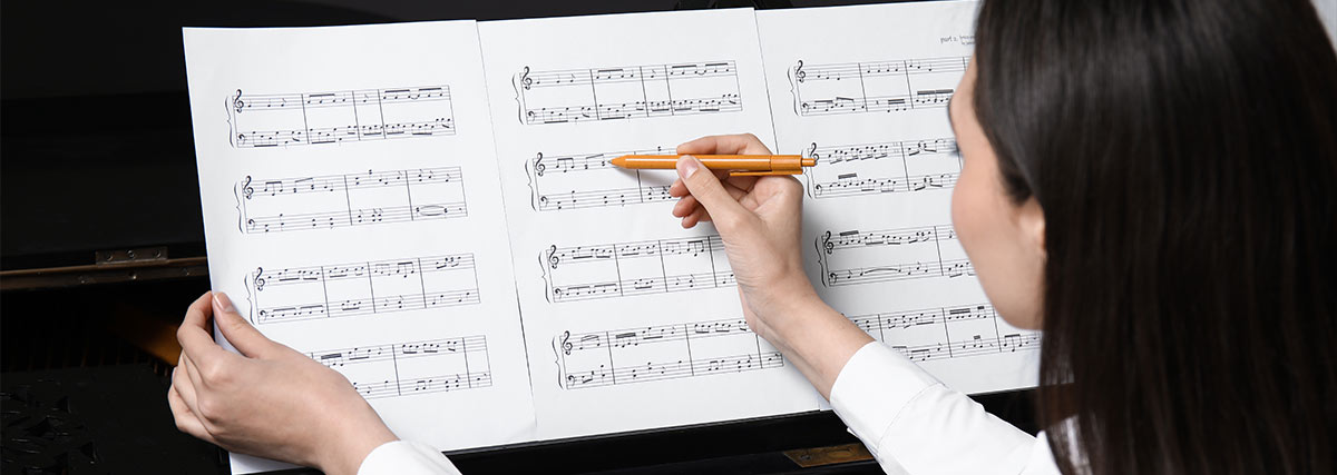 Woman writing on sheet music on the piano