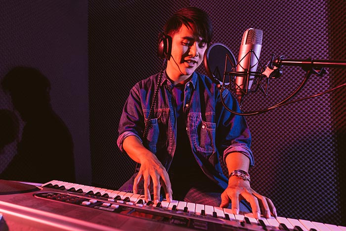Young man playing piano while singing feat